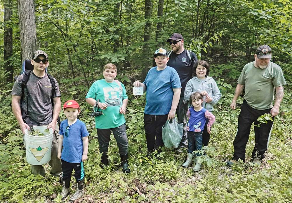 a group of volunteers pose in the copeland forest where they were helping pull the garlic mustard plants